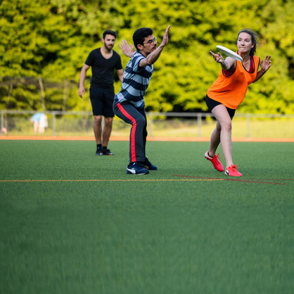 Gruppe von Ultimate Frisbee-Spielern, eine Frau kurz vor dem Abwurf der Frisbee