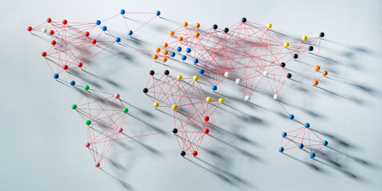 The outlines of the earth's continents are marked out on a white surface with needles and colored threads.